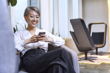 Businesswoman using smartphone smiling - CUF08746