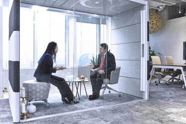 Colleagues having meeting in glass pod in office - CUF08747