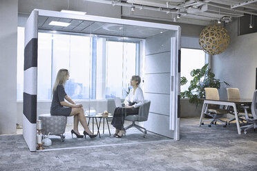 Colleagues having meeting in glass pod in office - CUF08748