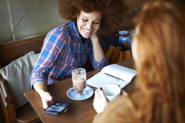 Freunde mit Smartphone entspannen sich im Cafe - CUF08776