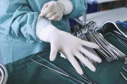 Surgeon putting on surgical gloves in maternity ward operating theatre - CUF08799