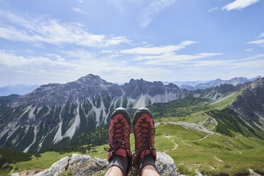 Personal perspective of female hiker's hiking boots over valley in Tannheim mountains, Tyrol, Austria - CUF08816