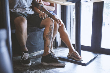 Taille nach unten eines multiethnischen Hipster-Paares in einem Café mit der Hand auf dem Knie des anderen, Shanghai French Concession, Shanghai, China - CUF08845