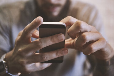 Hands of young man holding smartphone, close up - CUF08850