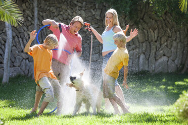 Familie besprüht Hund mit Wasser aus dem Schlauch - CUF08867