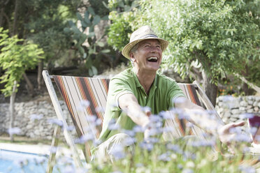 Mann im Garten sitzt im Liegestuhl und lacht - CUF08878