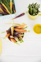 Blick von oben auf frische bunte Karotten und Spargel auf dem Küchentisch - CUF08905