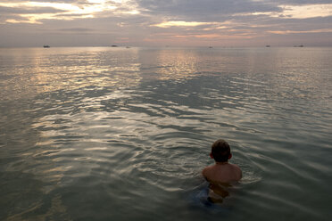 Thailand, boy swimming in the at sunset - MMIF00071