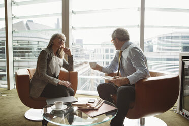 Businessman and businesswoman in coffee area in office, London, UK - CUF08948