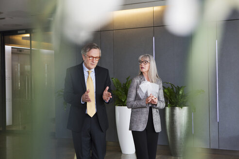 Businessman and businesswoman having discussion while walking - CUF08955