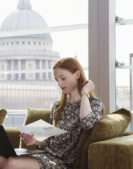 Geschäftsfrau mit Laptop auf einem Bürosofa, London, UK - CUF09030