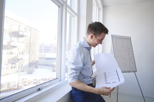 Architekt im Büro mit Blick auf einen Bauplan - CUF09048