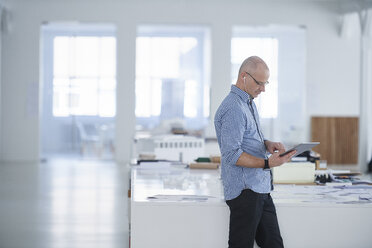 Man in open plan office using digital tablet - CUF09069