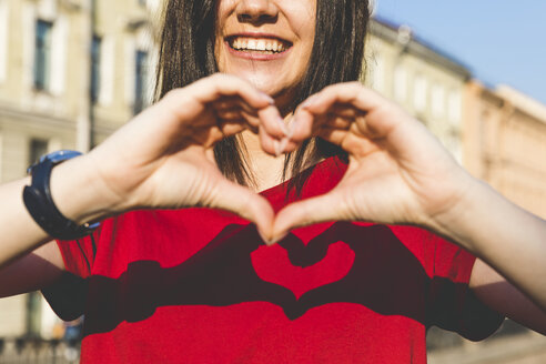 Woman's hands shaping heart, shadow on red t-shirt - WPEF00259