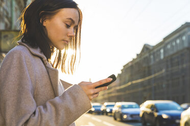 Russia, St. Petersburg, young woman using smartphone in the city - WPEF00262