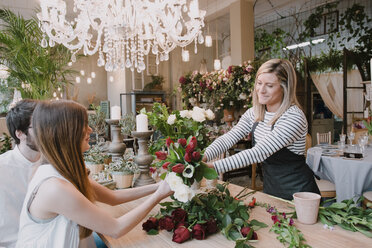 Florist in flower shop, handing flowers to customer - CUF09142