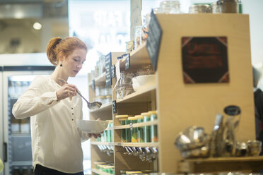 Woman using self service dispensers in shop - CUF09155