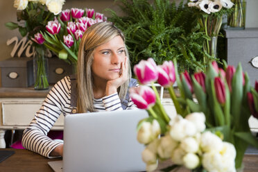Floristin in einem Blumenladen, mit Laptop, gelangweilter Gesichtsausdruck - CUF09157