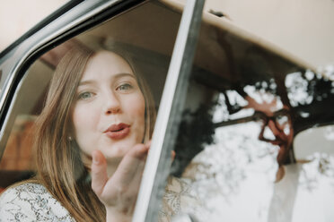 Couple in passengers seat of car, woman blowing kiss - CUF09160