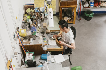 High angle view of male jeweller using blow torch at workbench - CUF09232