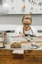 Juwelierin bei der Arbeit mit Miniaturhandwerkzeug an der Werkbank - CUF09246