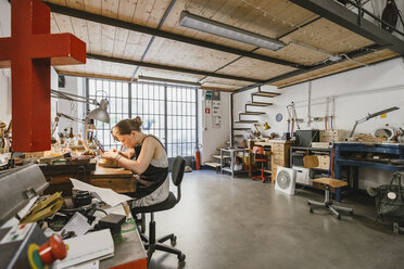 Female jeweller working at jewellery workshop workbench - CUF09265