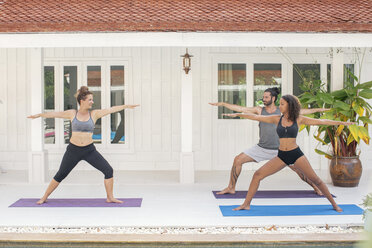 Two women and a man practicing yoga on terrace - MOMF00417