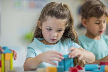 Konzentriertes Mädchen spielt mit Bauklötzen im Kindergarten - ZEF15431
