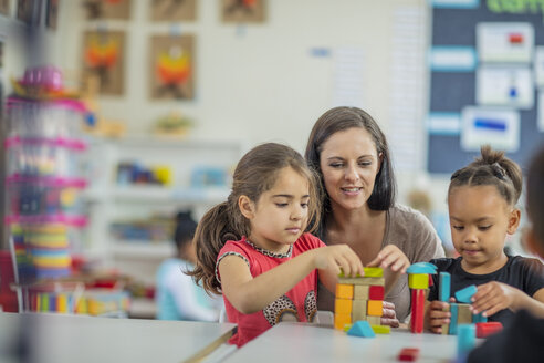 Pre-school teacher playing with girls in kindergarten - ZEF15438