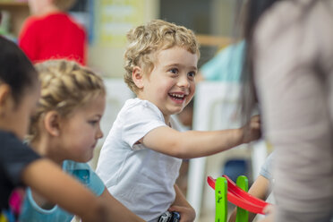 Fröhlicher Junge mit anderen Kindern und Vorschullehrerin im Kindergarten - ZEF15441