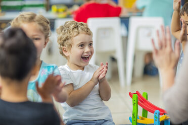 Glückliche Kinder und Vorschullehrerin klatschen im Kindergarten in die Hände - ZEF15442