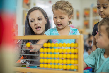 Vorschullehrerin mit Kindergartenkindern, die einen Abakus benutzen - ZEF15445