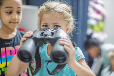 Girl holding binoculars in kindergarten - ZEF15449