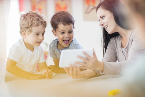 Vorschullehrerin zeigt Mini-Tablet an glückliche Jungen im Kindergarten - ZEF15466