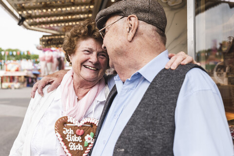 Happy senior couple with gingerbread heart on fair stock photo