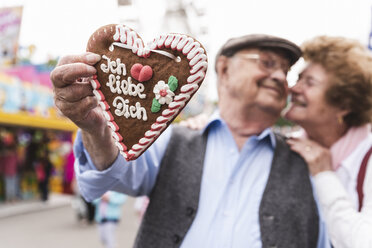 Hand eines älteren Mannes, der ein Herz aus Ingerbrot auf einem Jahrmarkt hält, Nahaufnahme - UUF13743