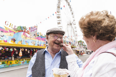 Porträt eines glücklichen älteren Mannes, der sich mit seiner Frau auf dem Jahrmarkt amüsiert - UUF13745