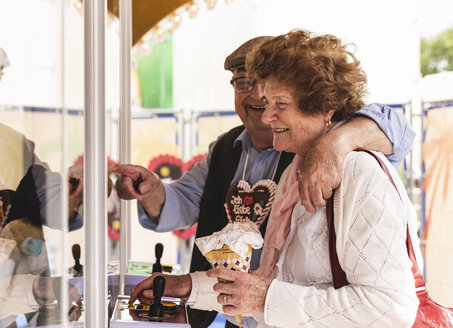 Senior couple having fun with gaming machine on fair - UUF13747