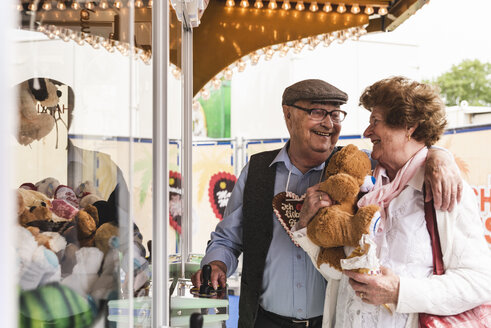 Happy senior couple with prize on fair - UUF13748