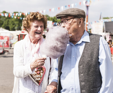 Älteres Paar auf dem Jahrmarkt, das Zuckerwatte genießt - UUF13760