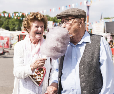 Senior couple on fair enjoying cotton candy - UUF13760