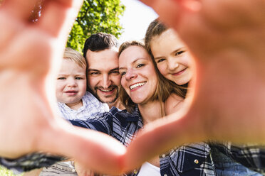 Porträt einer glücklichen Familie, die durch einen Fingerrahmen schaut - UUF13762