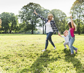 Active happy family walking hand in hand in a park - UUF13770