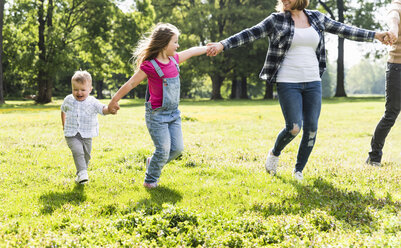 Aktive glückliche Familie, die Hand in Hand in einem Park spazieren geht - UUF13772