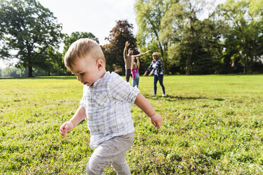 Boy walking in a park with family in background - UUF13775