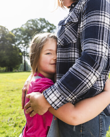 Tochter umarmt Mutter in einem Park, lizenzfreies Stockfoto