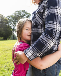 Daughter hugging mother in a park - UUF13778