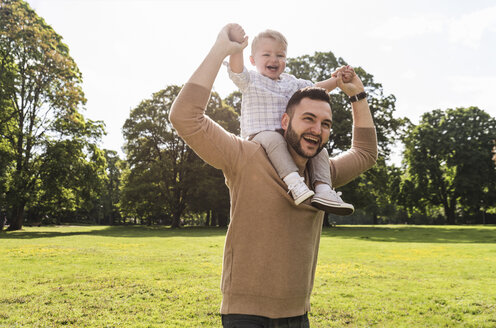 Glücklicher Vater trägt seinen Sohn auf den Schultern in einem Park - UUF13779