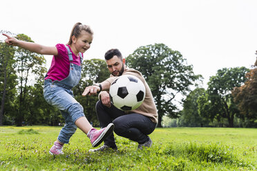 Vater spielt Fußball mit Tochter in einem Park - UUF13786