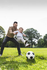 Glücklicher Vater spielt mit seinem Sohn im Park Fußball - UUF13787